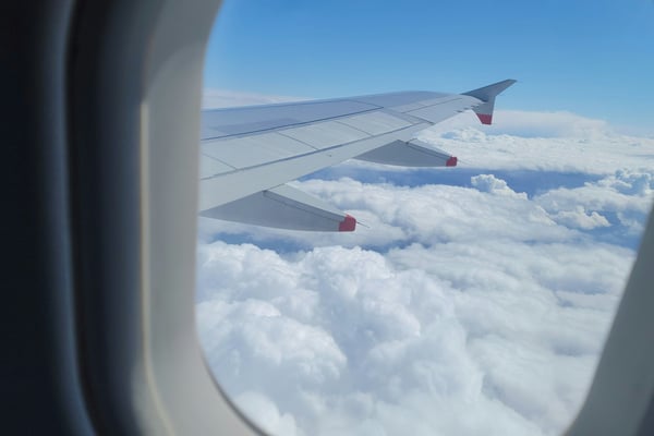 Airplane wing over a sea of clouds viewed from a passenger window
